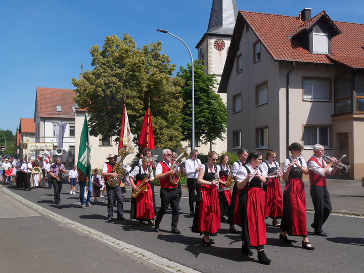 Die Prozession in einer Straße. Voraus geht die Musikkapelle.