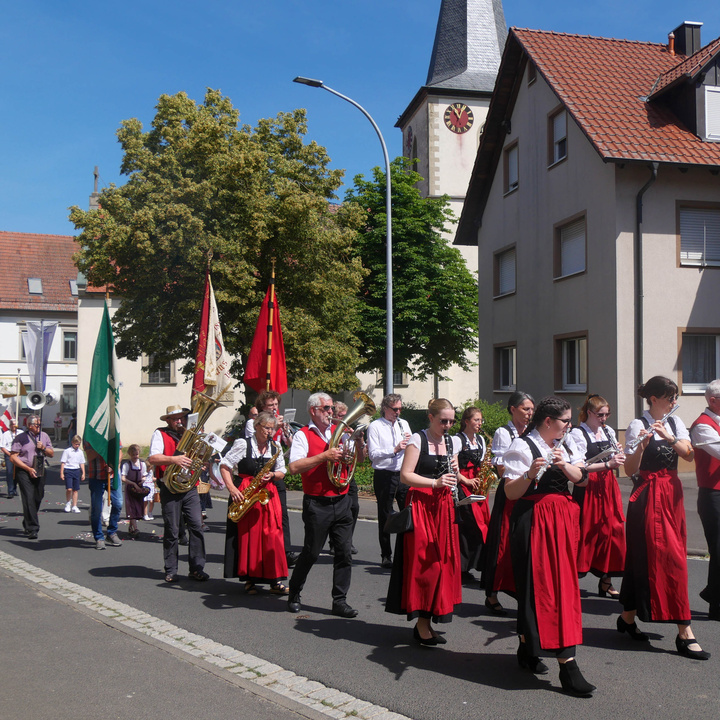 Die Prozession in einer Straße. Voraus geht die Musikkapelle.