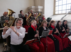 Auf der Empore sitzen Musizierende in Bänken und spielen ihr Instrument.