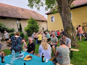 Mehrere Menschen sitzen auf einer Wiese, unterhalten sich und essen