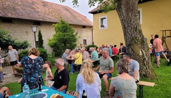 Mehrere Menschen sitzen auf einer Wiese, unterhalten sich und essen