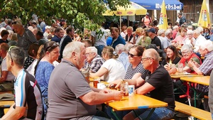 Viele Menschen sitzen an Bierbänken und unterhalten sich.