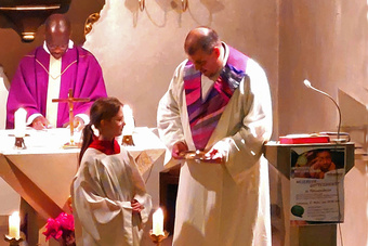 Der Pfarrer und der Pastoralreferent wenden sich der neuen Ministrantin zu. Sie steht in der Mitte.