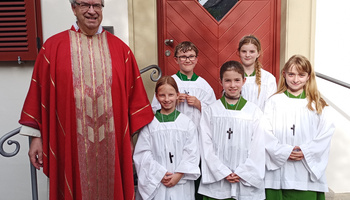 Gruppenbild mit Pfarrer Rügamer im roten Messgewand und den fünf neuen Ministrant:innen.