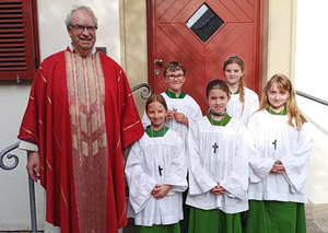 Gruppenbild mit Pfarrer Rügamer im roten Messgewand und den fünf neuen Ministrant:innen.