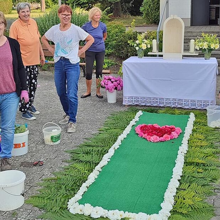 Vier Frauen stehen um einen Teppich aus Blumen und Blättern.