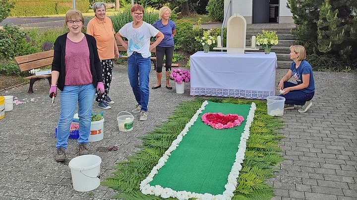 Vier Frauen stehen um einen Teppich aus Blumen und Blättern.