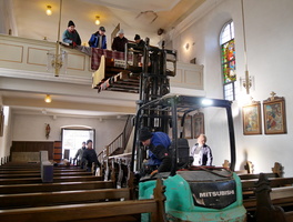 Ein Gabelstapler steht in der Kirche. Die Orgel wird gerade auf die ausgefahrene Gabel gelegt.