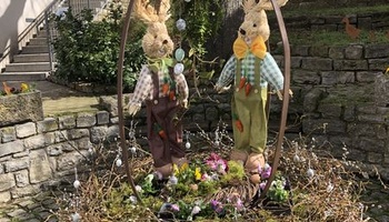 Der Osterbrunnen in Püssensheim mit zwei Hasen, angemalten Eiern und Blumen.