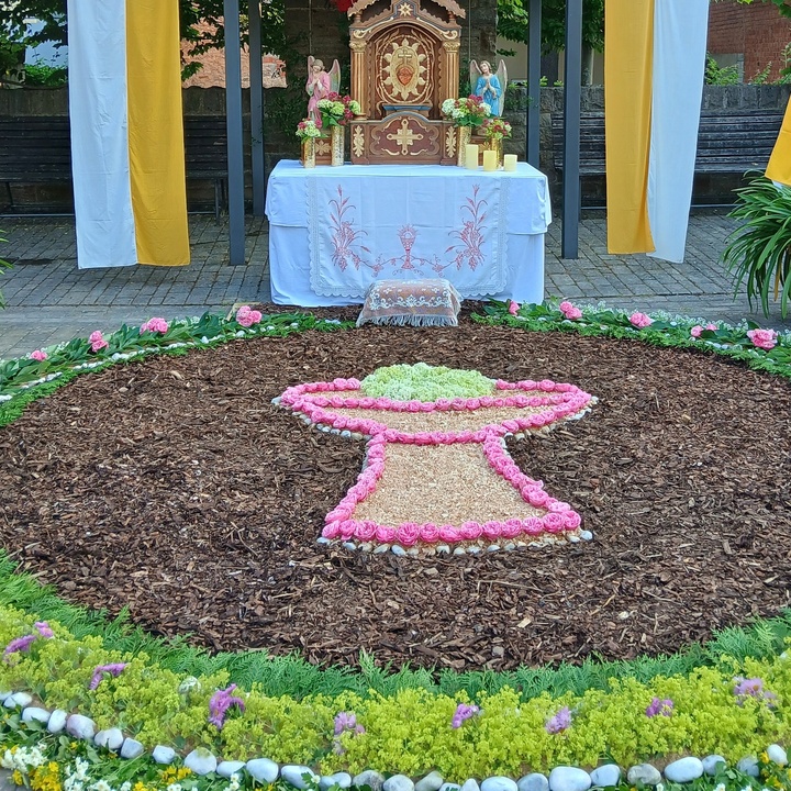 Ein großer bunter Blumenteppich vor einem Altar.