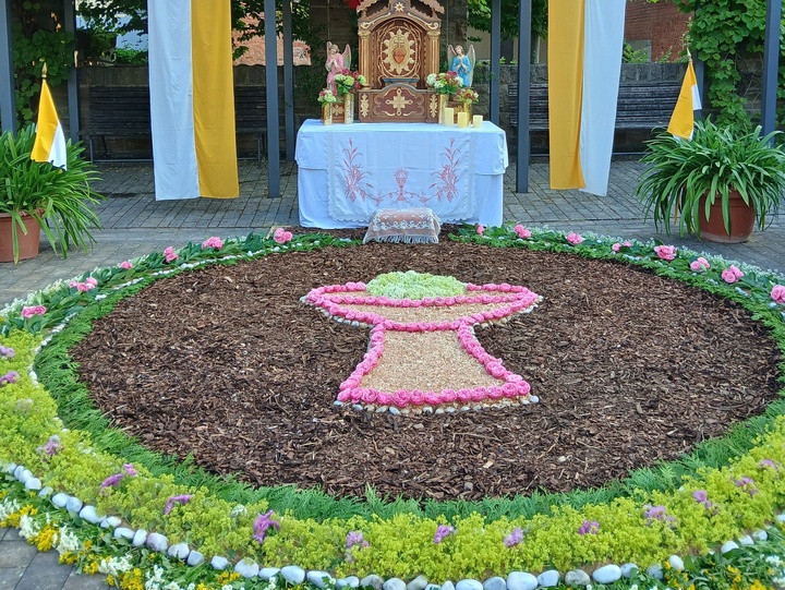 Ein großer bunter Blumenteppich vor einem Altar.