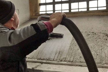 Ein Mann saugt eine Fensternische sauber.