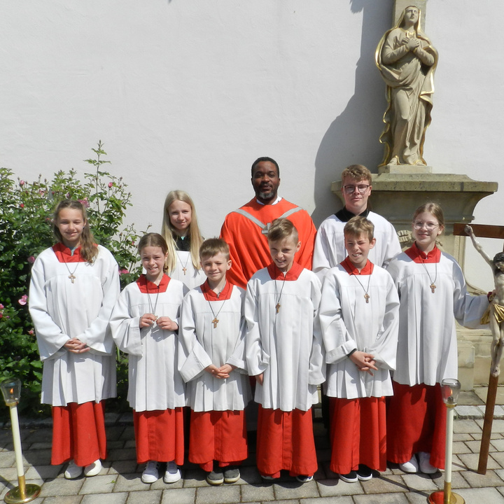 Gruppenbild der neuen Ministrant:innen im Gewand zusammen mit Kaplan Louis Odidi.