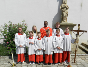 Gruppenbild der neuen Ministrant:innen im Gewand zusammen mit Kaplan Louis Odidi.