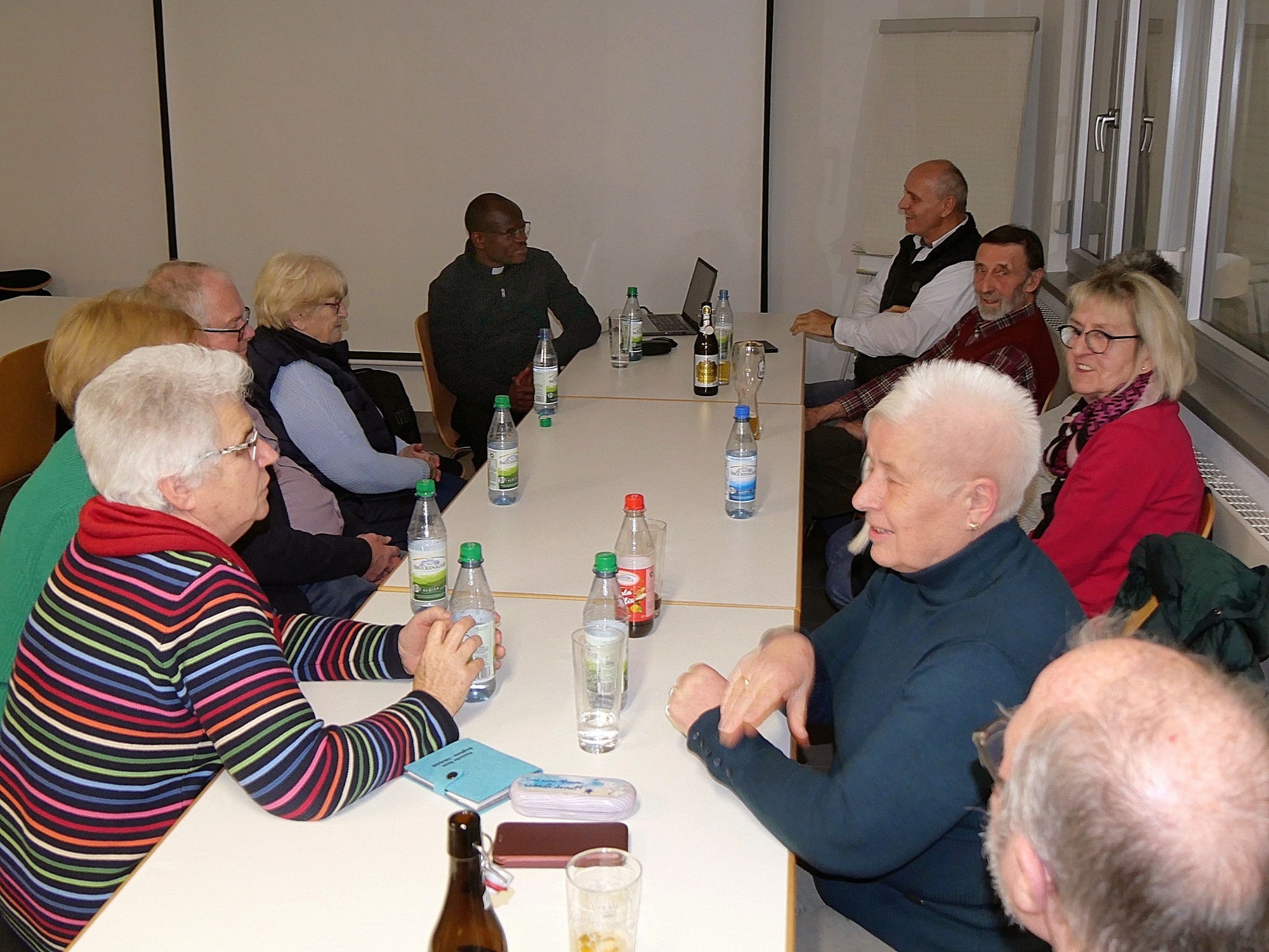 Eine kleine Gruppe sitzt um einen Tisch im Feuerwehrhaus von Gramschatz.