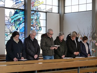 In einer Bank in der Kirche stehen sechs Personen und singen.