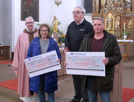 In der Burggrumbacher Kirche werden zwei große symbolische Schecks übergeben. 
