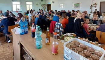 Ein großer Raum ist gefüllt mit vielen Menschen, die gemeinsam Essen. Im Vordergrund sind Muffins zu sehen.