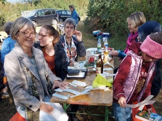 An einem Biertisch im Freien sitzen Menschen beieinander
