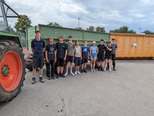 Gruppenbild der Altpapiersammler:innen neben einem Traktor und vor Containern