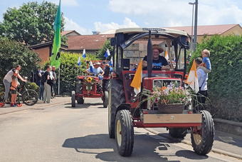 Man sieht geschmückte Oldtimer-Traktoren und Menschen am Straßenrand.
