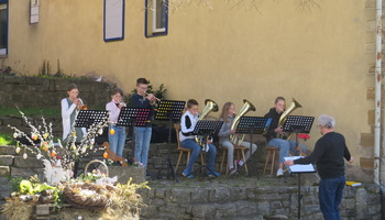 Osternestchensuche nach dem Festamt von Father Louis am Osterbrunnen. Die Püssensheimer Juniorbläser unter Leitung von Markus Zitzmann spielten dazu ein Ständerle für die Gäste.