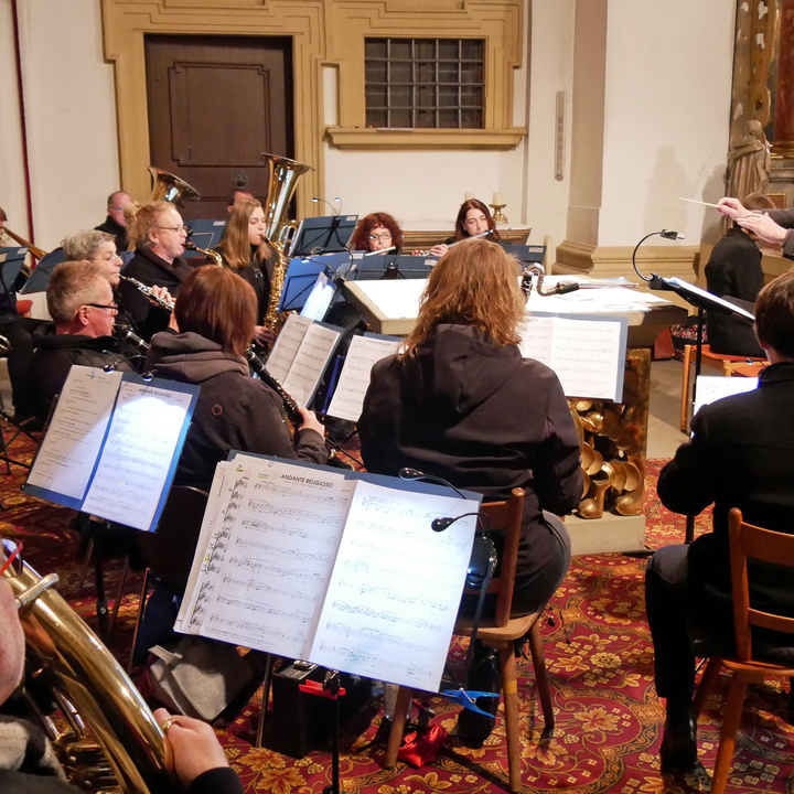 Blick auf das Orchester beim Spielen. Rechts steht der Dirigent.