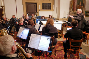 Blick auf das Orchester beim Spielen. Rechts steht der Dirigent.