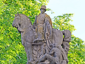 Ausschnitt des Kriegerdenkmals in Burggrumbach. Man sieht den heiligen Martin auf einem Pferd mit einem Helm auf dem Kopf. Er teilt seinen Mantel mit einem Bettler am Boden.