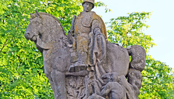 Ausschnitt des Kriegerdenkmals in Burggrumbach. Man sieht den heiligen Martin auf einem Pferd mit einem Helm auf dem Kopf. Er teilt seinen Mantel mit einem Bettler am Boden.