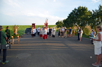 Auf dem Parkplatz vor der Kirche stehen in einem Rund mehrere Gläubige und beten oder singen.