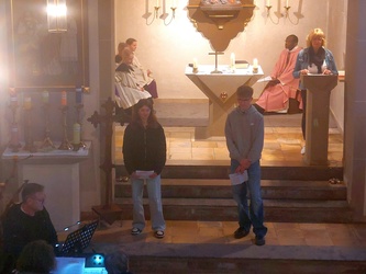 Zwei Kinder stehen auf den Altarstufen und lesen etwas vor.