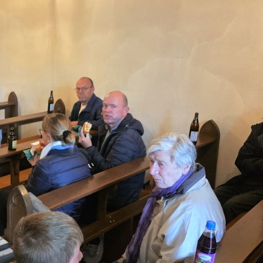 In den Kichenbänken sitzen Menschen und unterhalten sich.