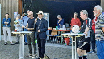 Der Moderator und der Bischof stehen an einem weißen runden Tisch. Bischof Franz Jung hat ein Mikrofon in der Hand.