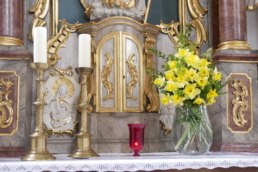 Eine rote Kerze steht neben dem Tabernakel im Seitenaltar der Hausener Pfarrkirche.