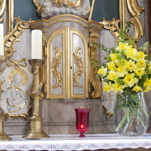 Eine rote Kerze steht neben dem Tabernakel im Seitenaltar der Hausener Pfarrkirche.