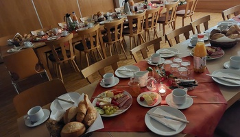 Ein schön vorbereiteter Früchstückstisch mit Geschirr, Wurst, Käse und einem Teelicht in der Mitte