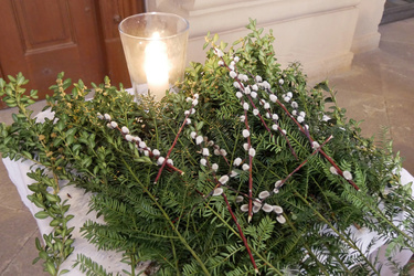 Auf einem kleinen Tisch liegen grüne Zweige und Palmkätzchen.