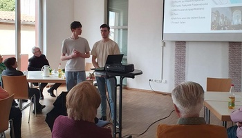 Zwei Jugendliche stehen in einer Runde und erzählen etwas.