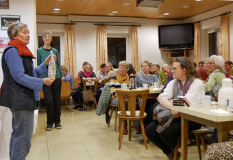 Eine Frau steht links und erklärt einer Gruppe Frauen auf der rechten Seite ihren Verein.
