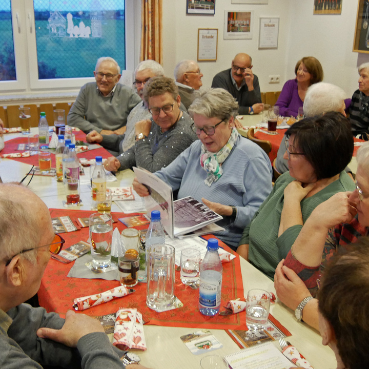 Um einen adventlich gedeckten Tisch sitzen Menschen