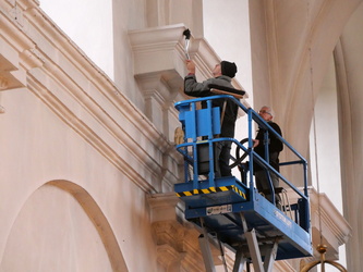 Zwei Männer beim Reinigen eines Mauervorsprungs in der Kirche.