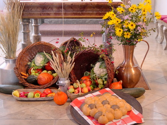Das Bild zeigt einen mit Ähren, Obst, Gemüse, Blumen und Brot geschmückten Altar in einer Kirche. 