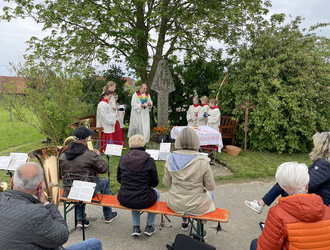 Bei diesem Bild blickt man über die Rücken von sechs Menschen nach vorn zu einem Bildstock. Dort stehen der Pastoralreferent und einige Ministraten neben einem Bildstock.
