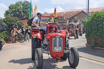 Eine ganze Reihe an Oldtimer-Traktoren sind zu sehen. Ganz vorn ist ein roter Traktor.