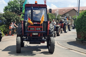 Eine ganze Reihe an Oldtimer-Traktoren fahren hintereinander.