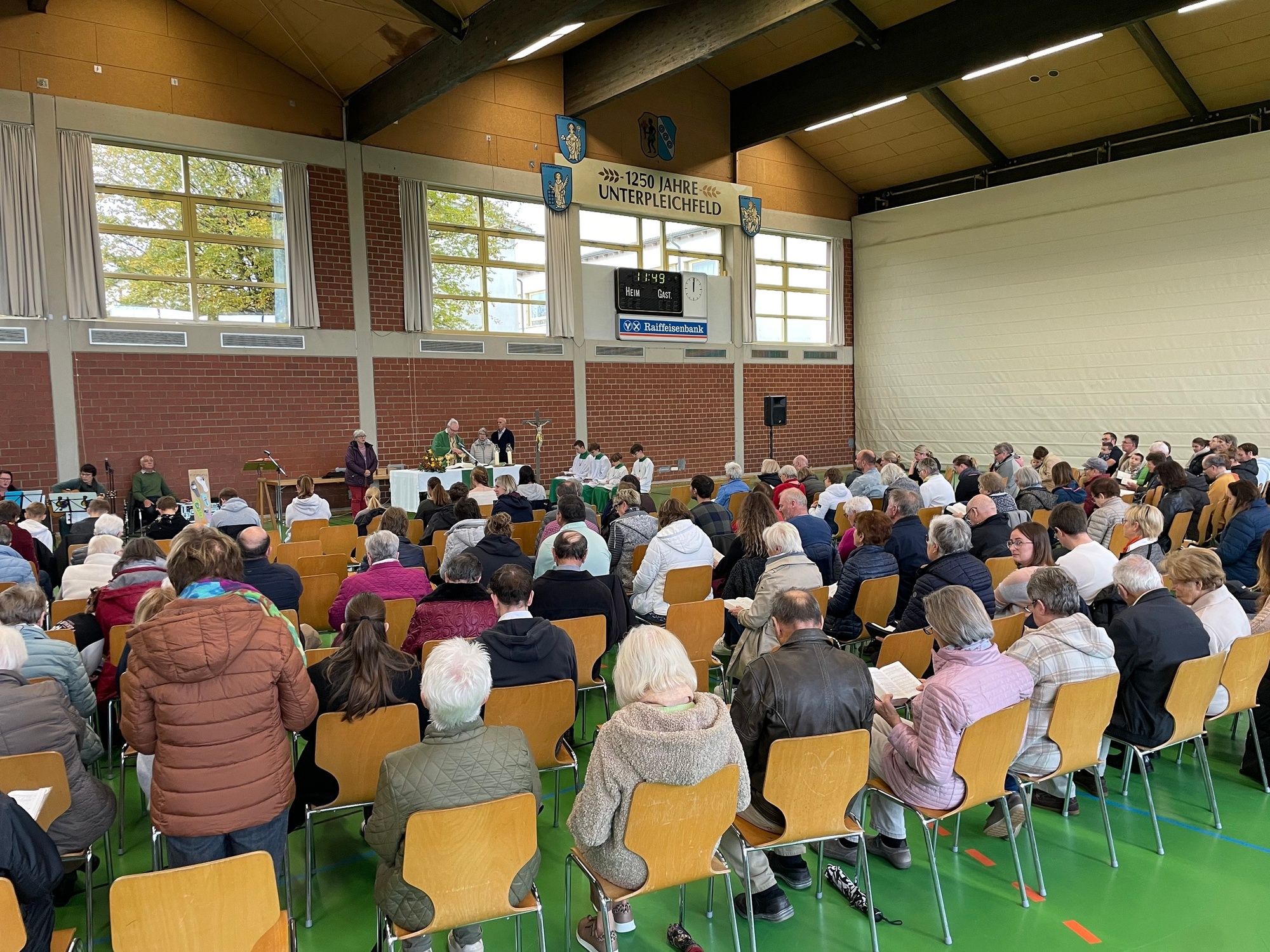 Blick von hinten in eine Halle hin zum Altartisch. Es wird gerade Gottesdienst gefeiert.