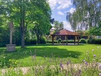 Blick über eine Wiese mit einem Pavillon im Hintergrund