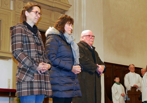 Drei Personen stehen im Altarraum und beten