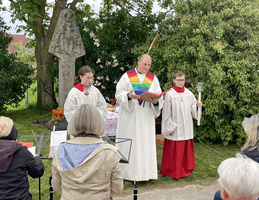 Der Pastoralreferent steht vor einem Bildstock und liest in der Bibel. Rechts und links von ihm sind Ministranten.